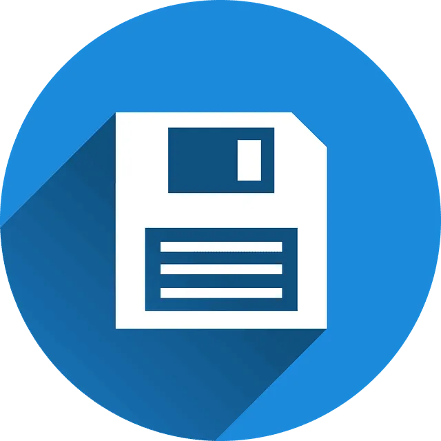 Icono de disquete blanco centrado sobre un círculo azul con sombra larga que sugiere guardado, respaldo de archivos y administración de contenidos, relacionado con Mantenimiento y optimización de páginas webs.
