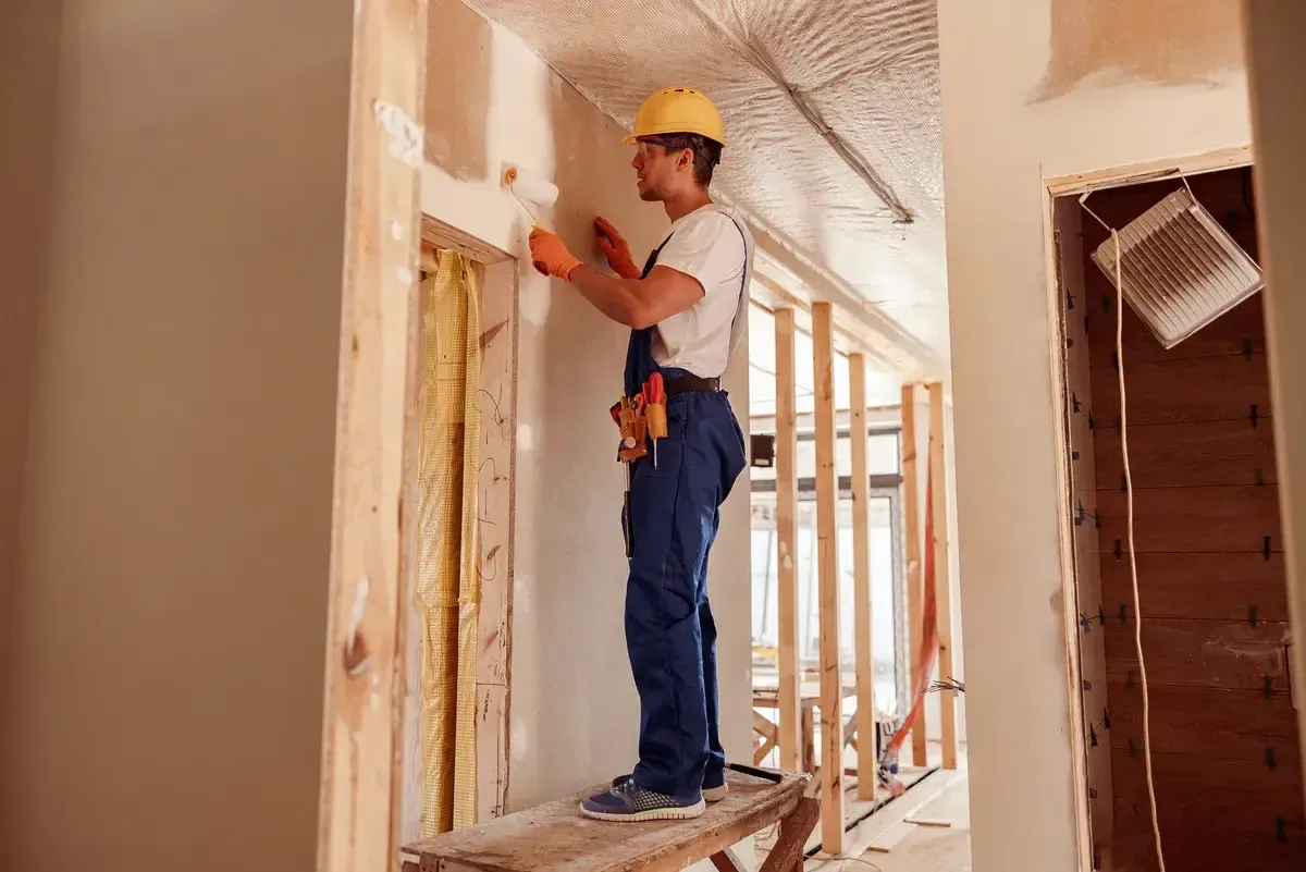 male-builder-painting-wall-in-house-under