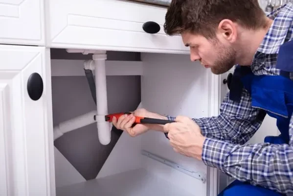 a plumber in West Chicago IL repairing the bathroom plumbing sink drain with an adjustable wrench
