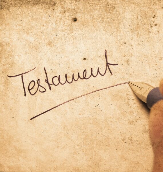 Une personne écrivant le mot testament sur un morceau de papier.