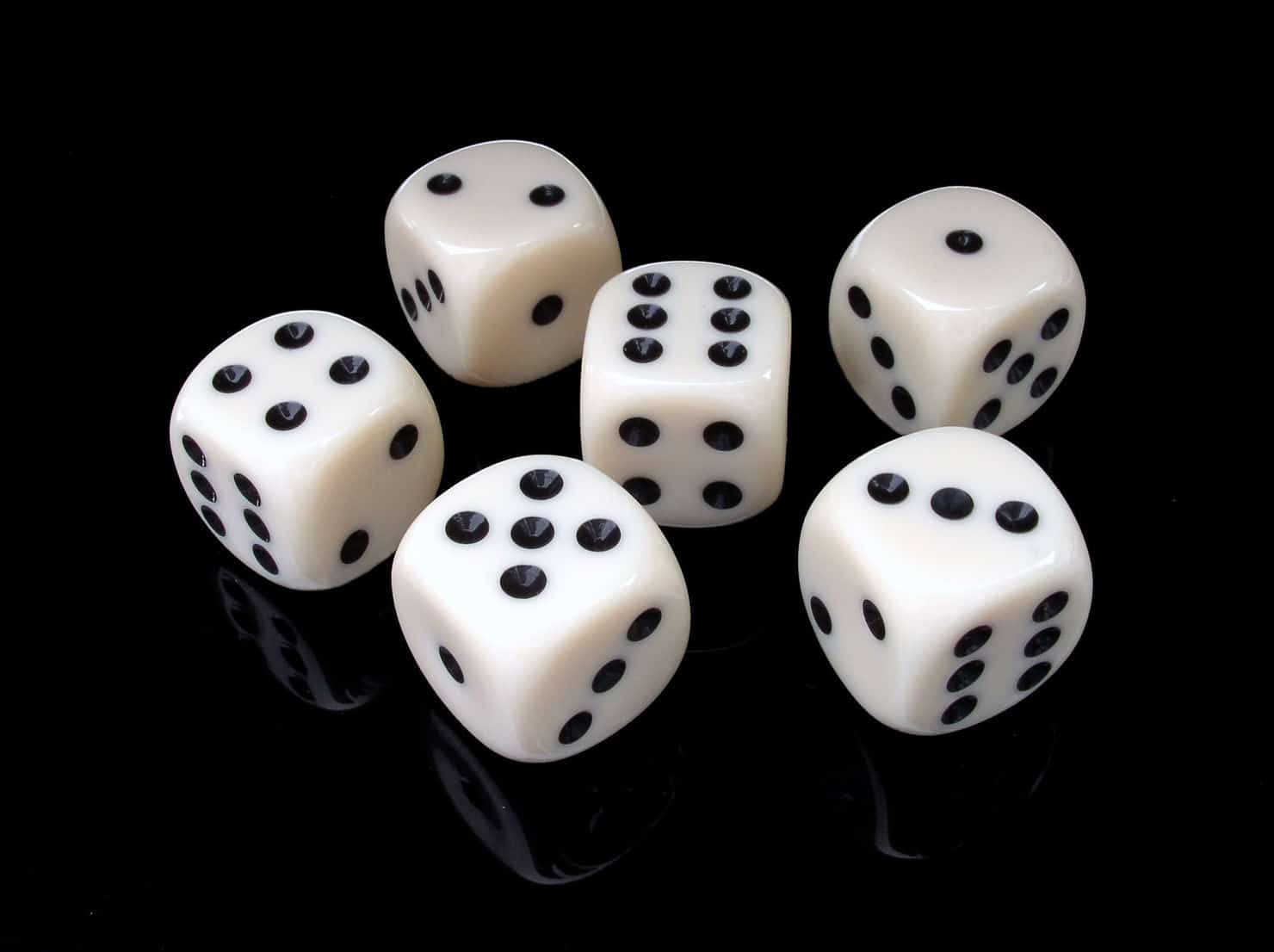 Six dés en plastique blanc sur surface noire pour une présentation.