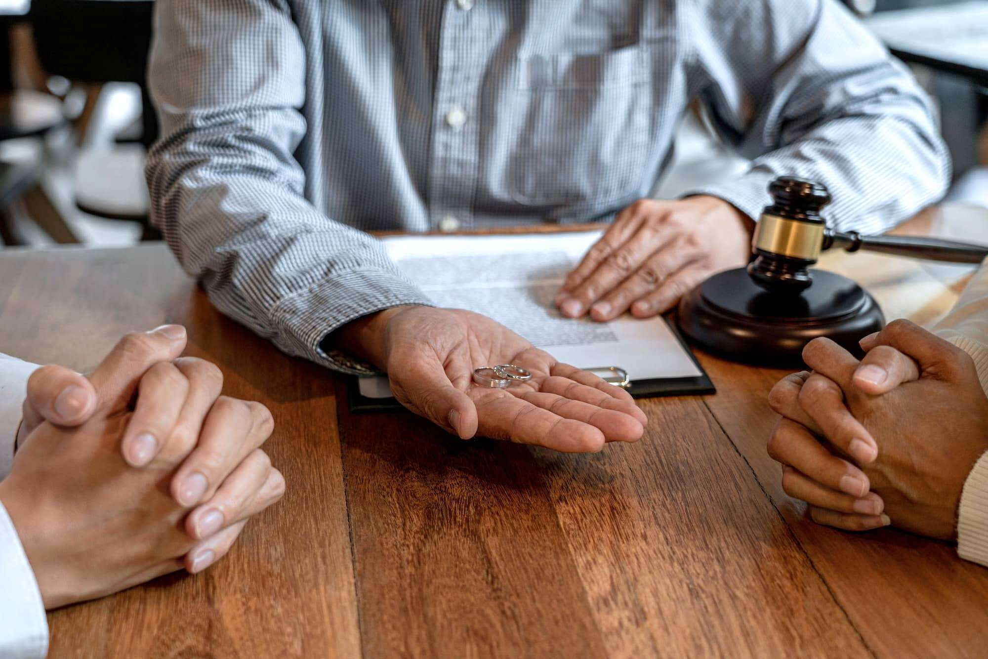 Deux personnes aimables assises à une table avec un juge leur donnant un marteau pendant leur procédure de divorce.