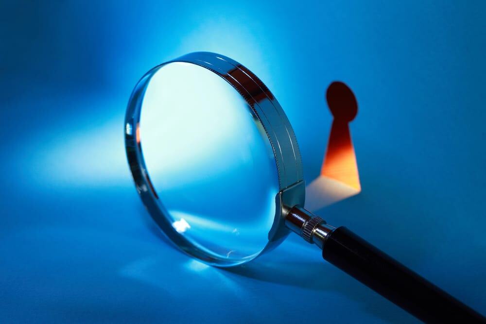 Loupe focalisée sur un petit pion rouge sur fond bleu, symbolisant le contrôle de l'autorité parentale.