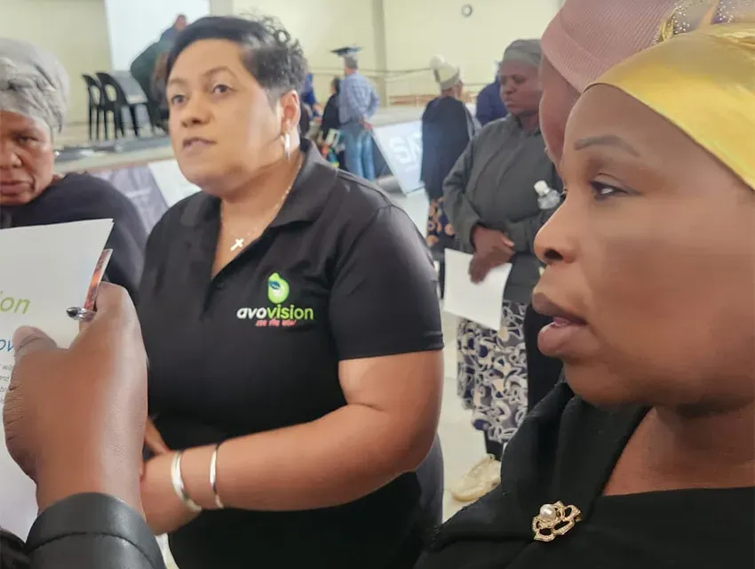 Avo Vision Women gather indoors, one in an Avo Vision shirt and another with a yellow headscarf. Avo Vision, a South Africa B2B leader, specializes in ECD, business & enterprise development, education.