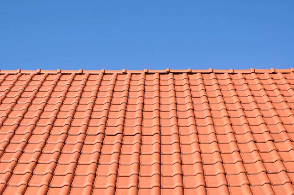 Toit de tuiles orange avec un ciel bleu clair en arrière-plan, mettant en valeur le travail minutieux d'un Couvreur à Valence d'Agen.