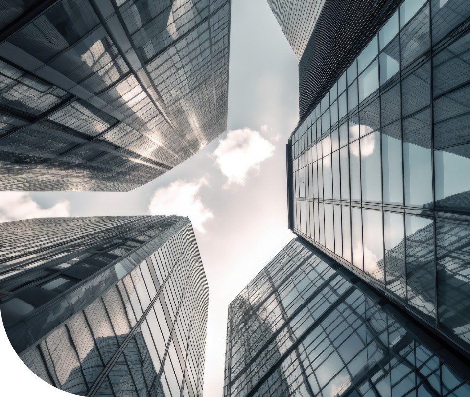 Upward view between tall glass office towers reflecting clouds in the sky