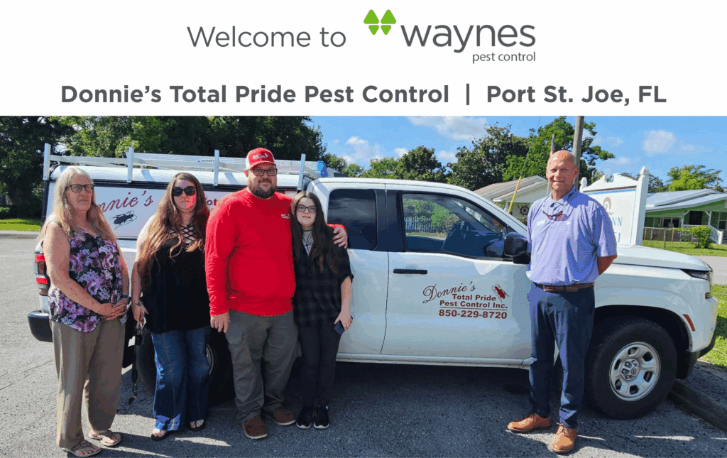 Five people standing beside a white pickup truck with Donnie's Total Pride Pest Control logo