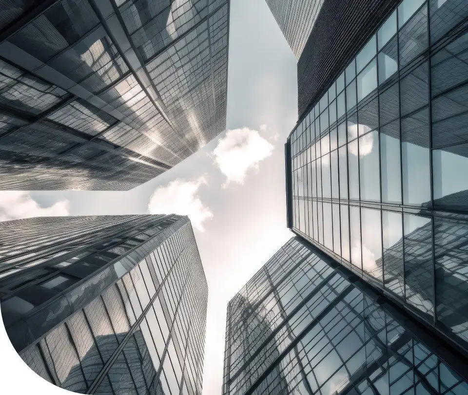 Upward view between tall glass office towers reflecting clouds in the sky