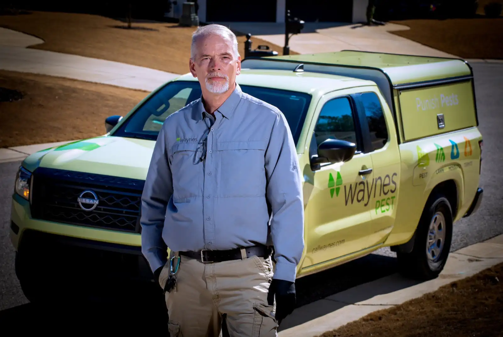 pest control professional standing in front of a waynes pest control work truck