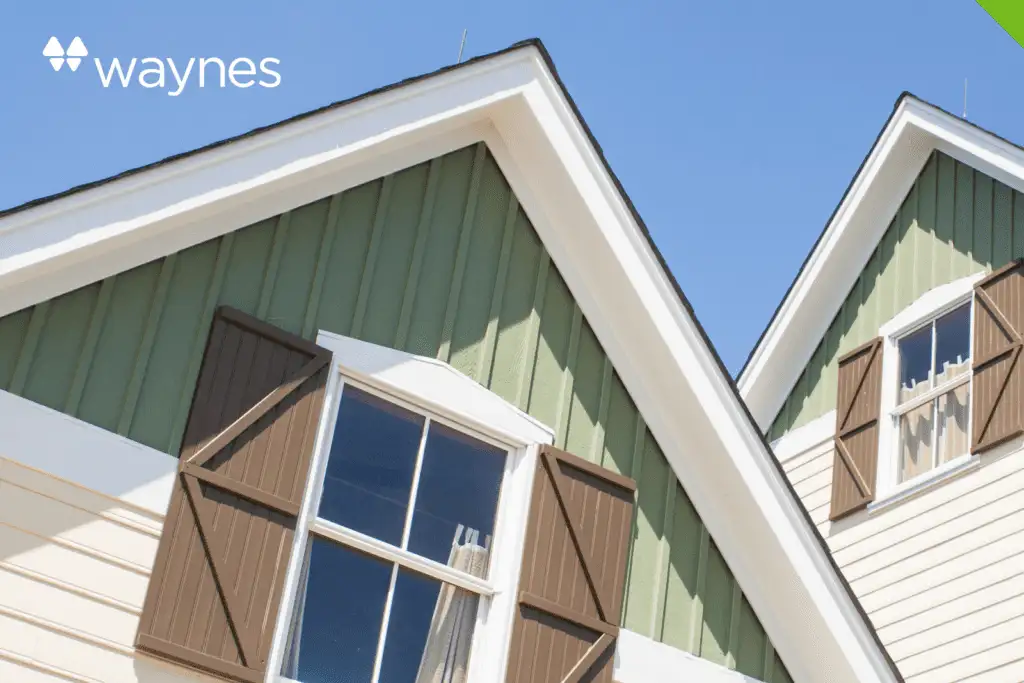 Green gable siding with white trim and brown shutters on windows under a clear blue sky, Waynes logo in top corner
