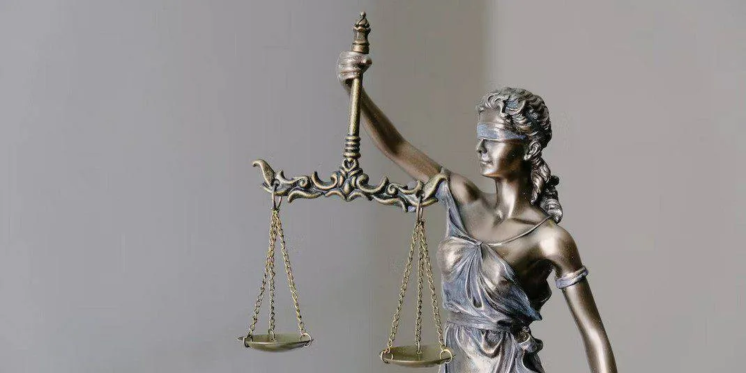 Blind Justice sculpture holding scales, symbolising fairness in financial and debt resolution.