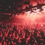 Large crowd at a Unreal Germany with industrial lighting, representing the global scale of the hard techno movement and current industry crisis.
