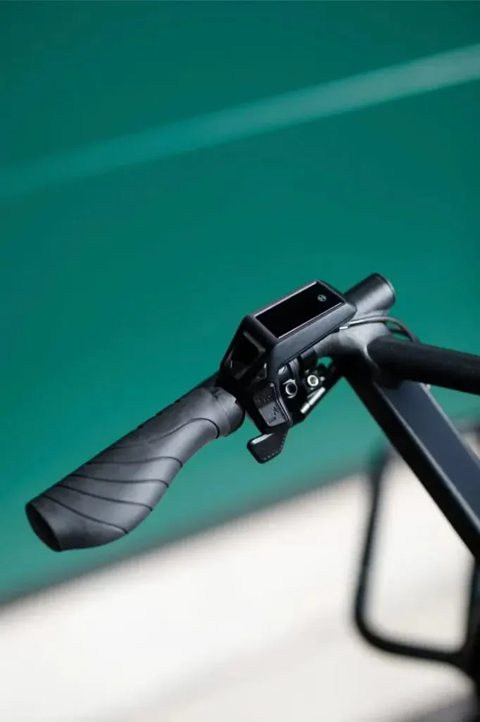 Primer plano de un manillar de bicicleta Moustache Lundi 20 Cargo con una pantalla electrónica montada sobre un fondo verde.