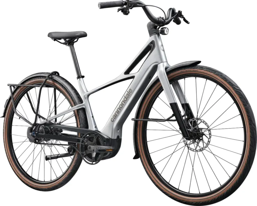 Bicicleta eléctrica Cannondale plateada con neumáticos marrones, guardabarros negros y frenos de disco mostrada en un ligero ángulo.