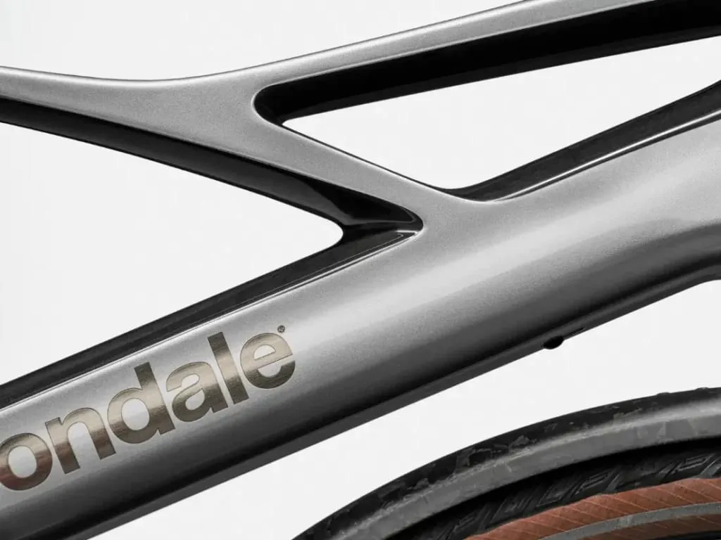 Primer plano de un cuadro metálico de bicicleta Cannondale FlyingV con el texto "Cannondale" y parte de un neumático visible.