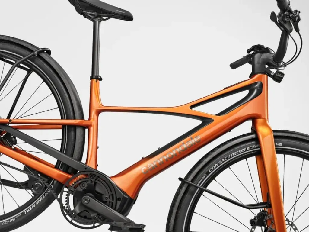Primer plano de un cuadro de bicicleta Cannondale FlyingV naranja con ruedas y guardabarros negros, visto de perfil.