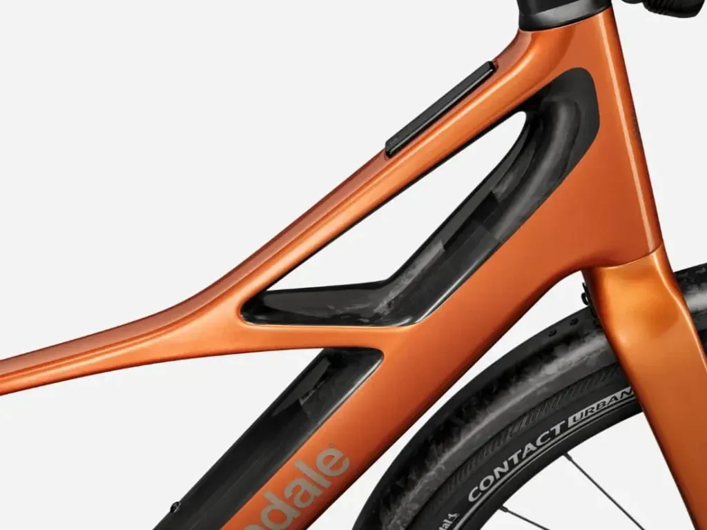 Primer plano de un cuadro de bicicleta Cannondale FlyingV de color naranja con un exclusivo diseño recortado sobre la rueda trasera y el neumático "Contact Urban" visible.