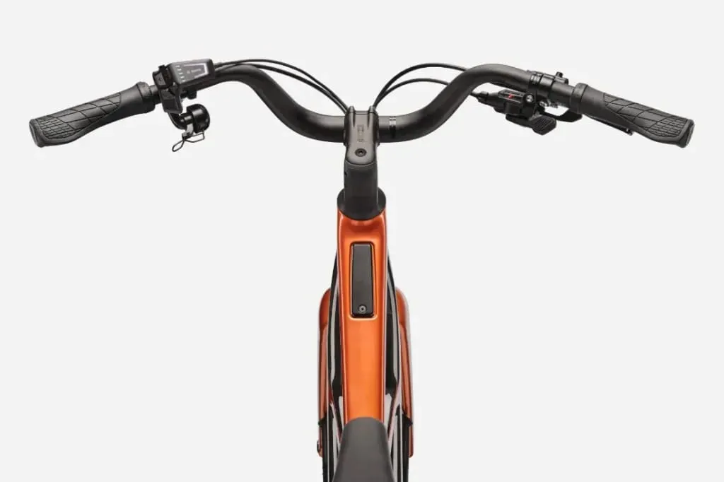 Vista del manillar negro, la pantalla y el llamativo cuadro naranja Cannondale FlyingV de una bicicleta eléctrica desde la perspectiva del ciclista.