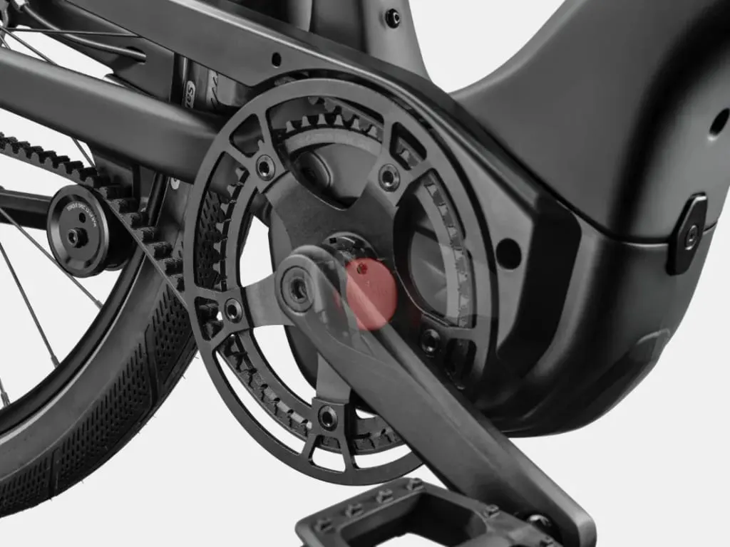 Primer plano de un plato y un pedal de bicicleta negros con sistema de transmisión por correa.