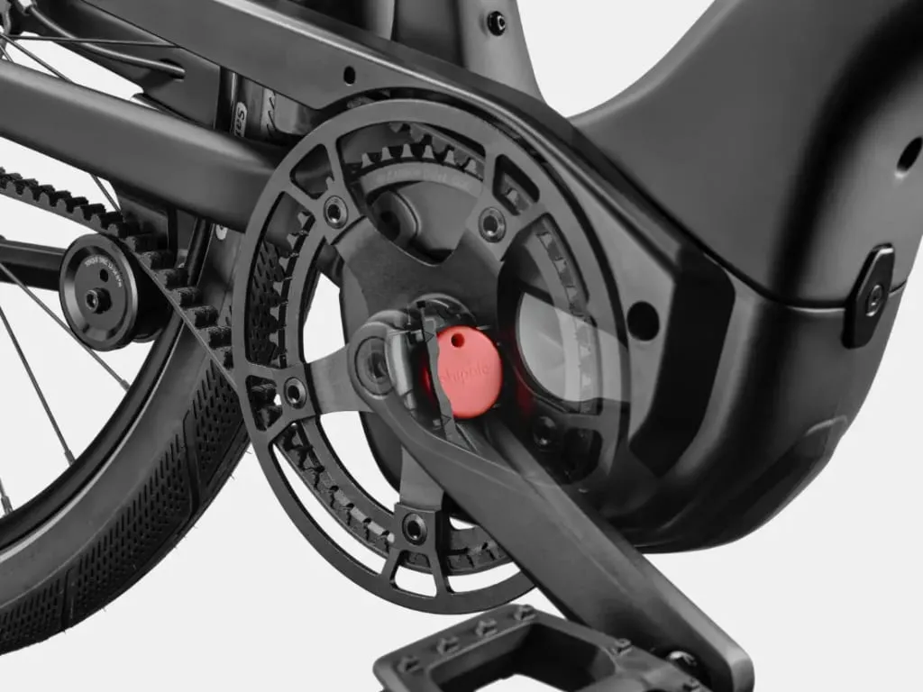 Primer plano de las bielas de una bicicleta con un dispositivo de seguimiento rojo colocado cerca del pedal.