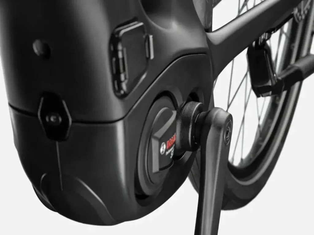 Primer plano de un motor y un brazo de biela de una bicicleta eléctrica Bosch fijados al cuadro, cerca de la rueda trasera.