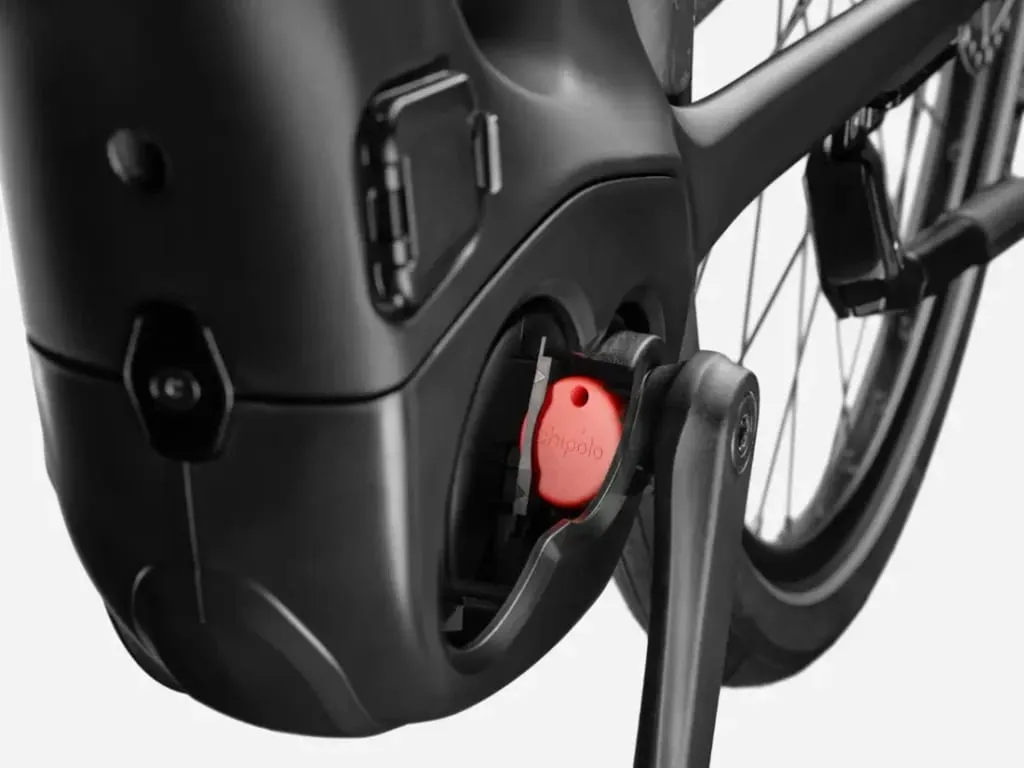Primer plano de un rastreador Chipolo acoplado cerca de la zona de la batería de una bicicleta eléctrica negra.