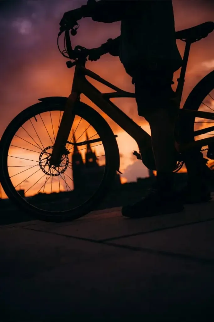 Silueta de una persona con una bicicleta Cannondale FlyingV al atardecer, enmarcada por un espectacular cielo naranja y morado de fondo.