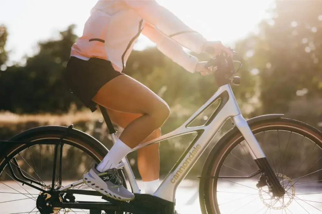 Saliendo al aire libre a la luz del sol en una Cannondale FlyingV, este ciclista lleva una chaqueta ligera, pantalones cortos y zapatillas deportivas para una mezcla perfecta de comodidad y estilo.