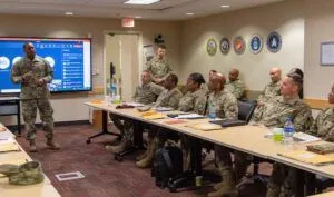 Uniformed military personnel seated in a briefing room while an instructor presents, What Does the Bible Say About Finance? Discover Biblical Principles for Financial Success.