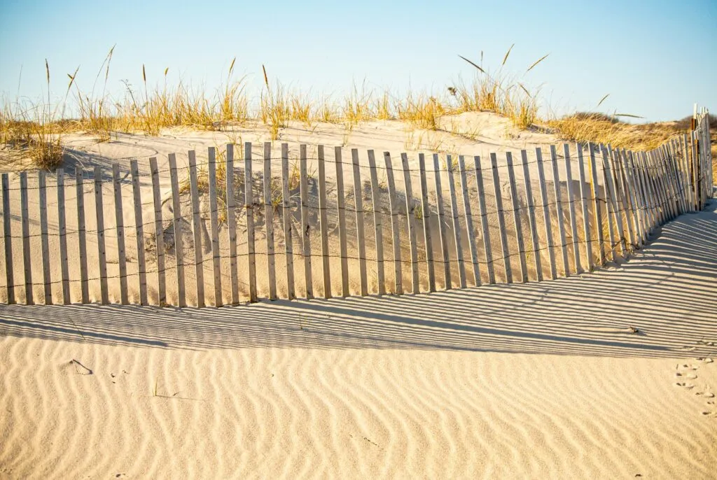 Wooden fence and sandy dunes at a Long Island beach symbolizing financial security and peace of mind