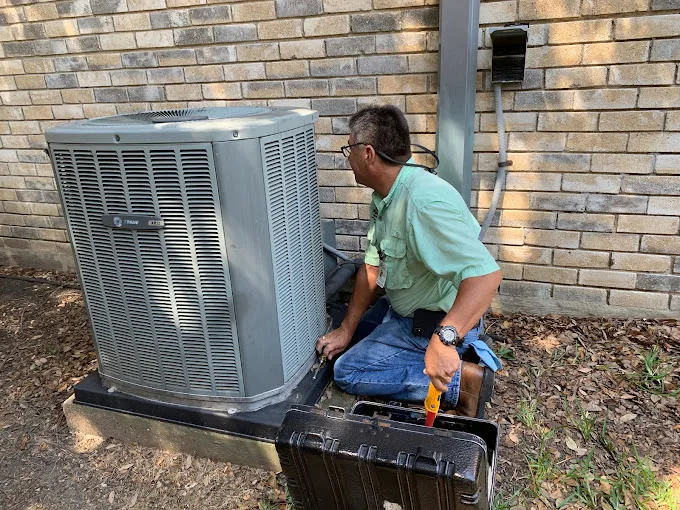 HVAC technician inspecting an outdoor AC condenser unit