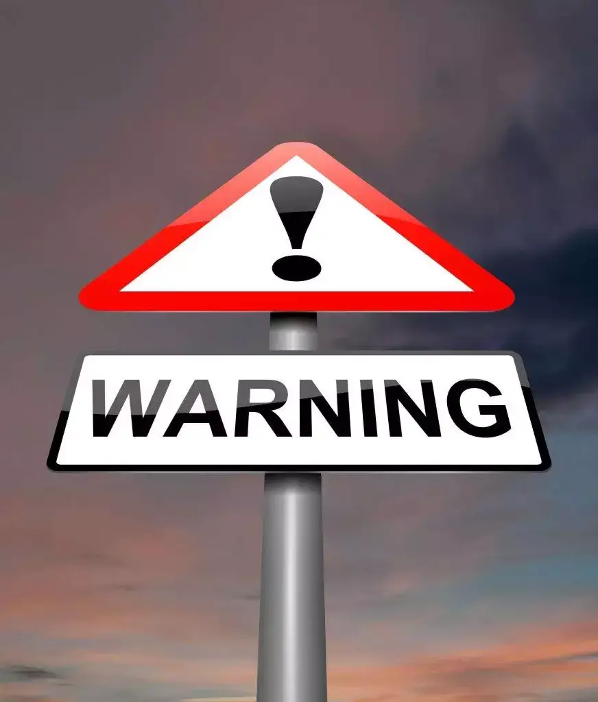 A warning sign with an exclamation mark against a cloudy sky background.