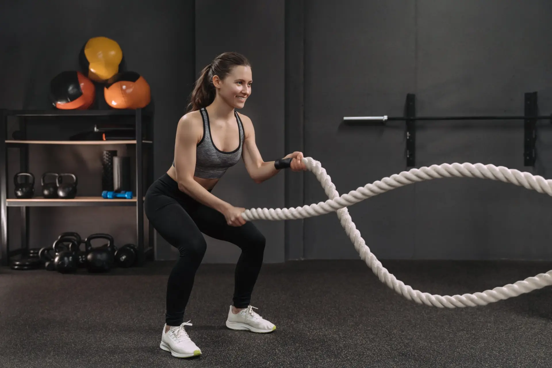 Woman doing deep squats with battle ropes