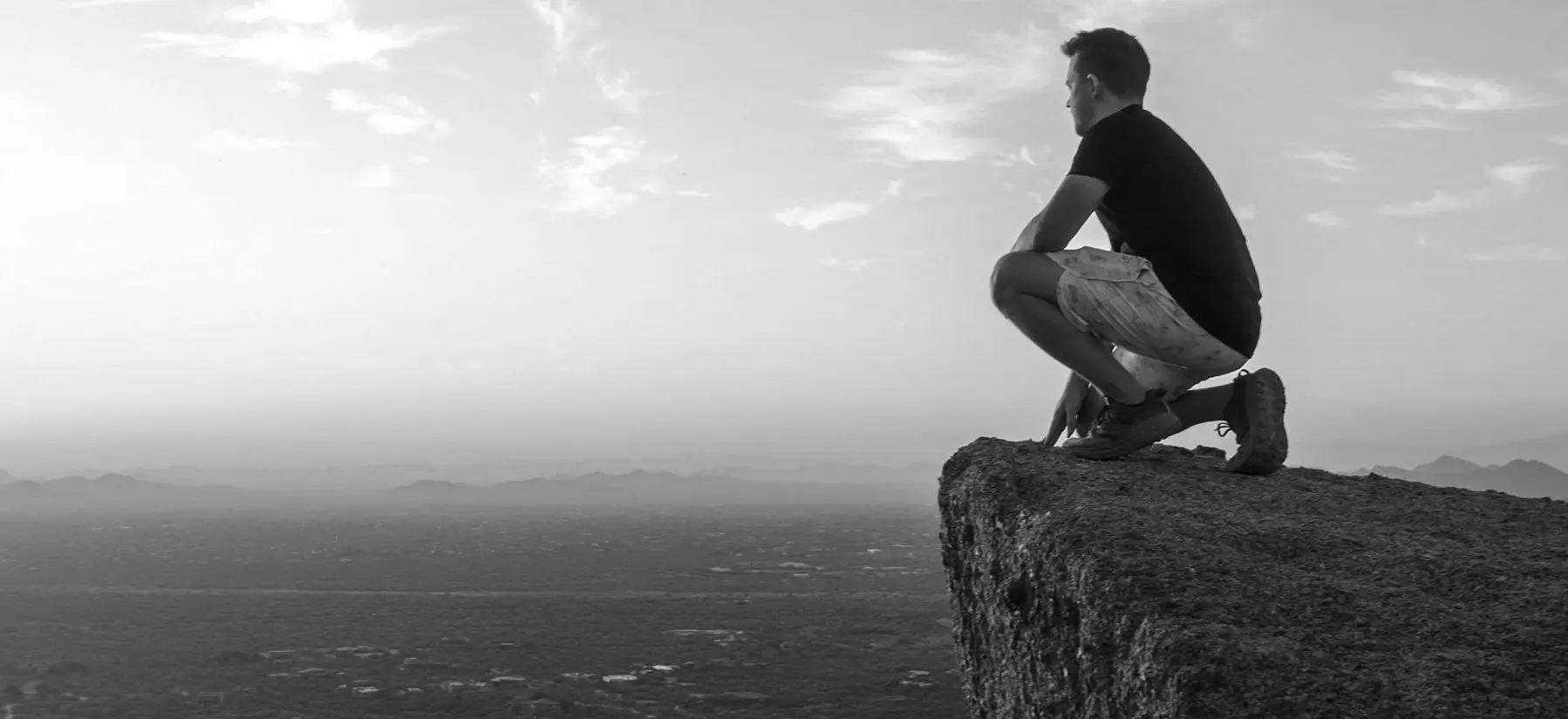 Man overlooking the Scottsdale desert from a rocky mountain ledge