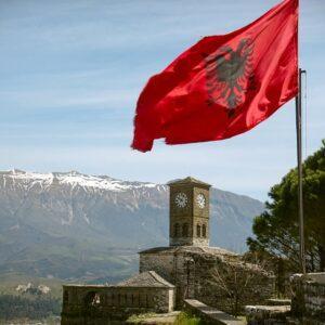 View of the Albanian Flag and the Gjirokaster Fortress with Mountains in the Background