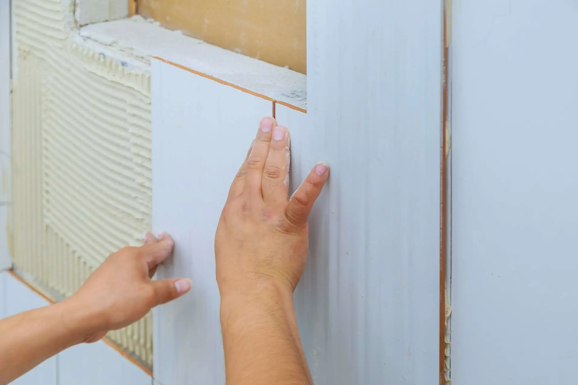 Fabre Occitanie - Une personne appliquant du mastic silicone Fabre sur l'espace entre un mur blanc et un climatiseur.