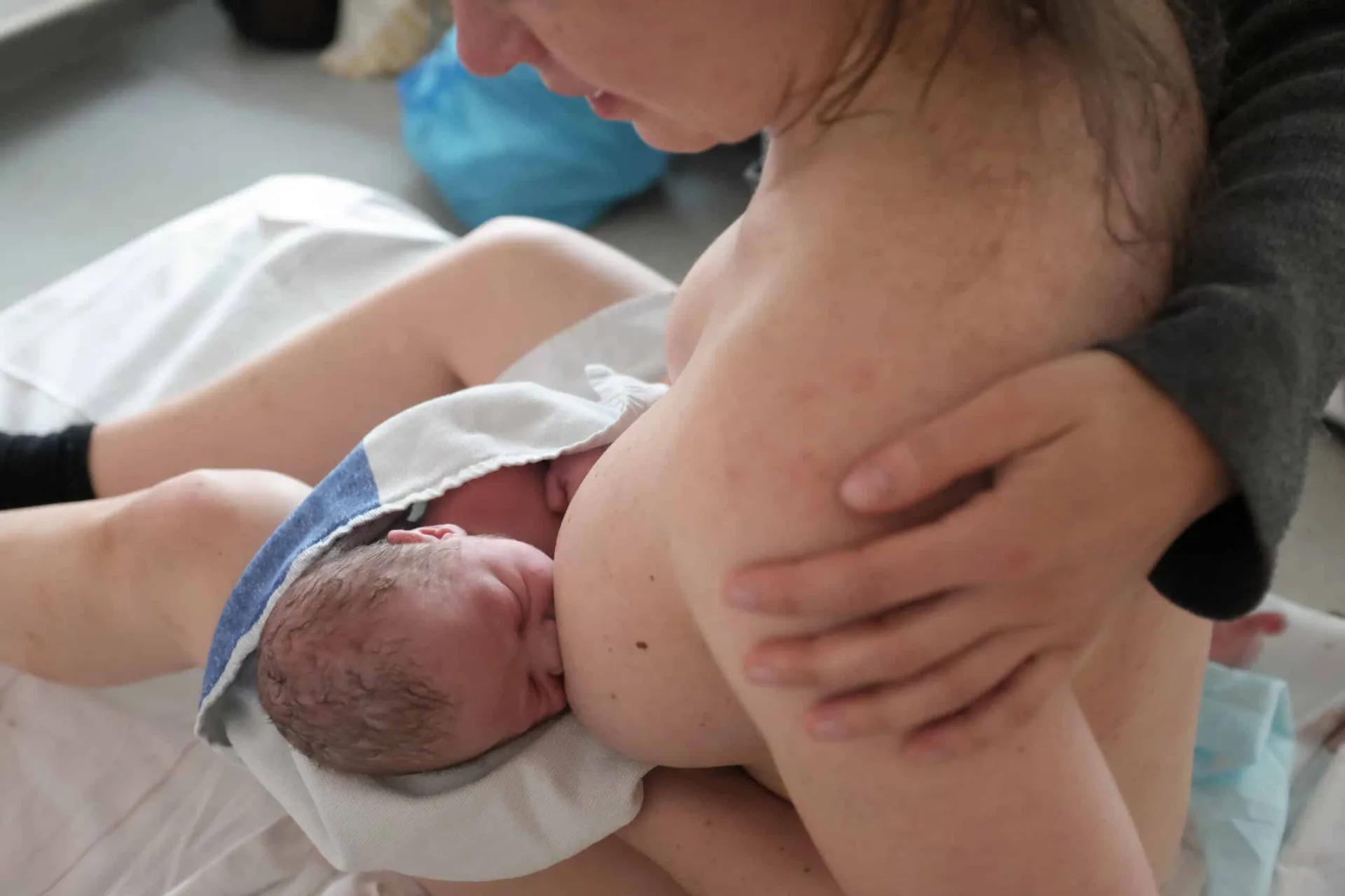 En nyfödd bebis ammar hud mot hud mot sin mammas bröst
