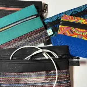 Colorful zippered pouches, some with woven mesh, one holds a white charging cable.