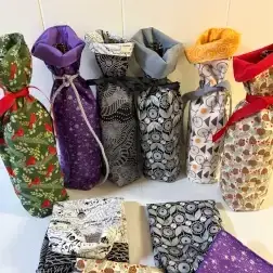Many patterned fabric bags, some tied, and folded fabric pieces in diverse colors.