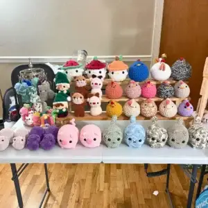 A large collection of handmade crocheted plush toys: chickens, pigs, cats, bears, and gnomes.