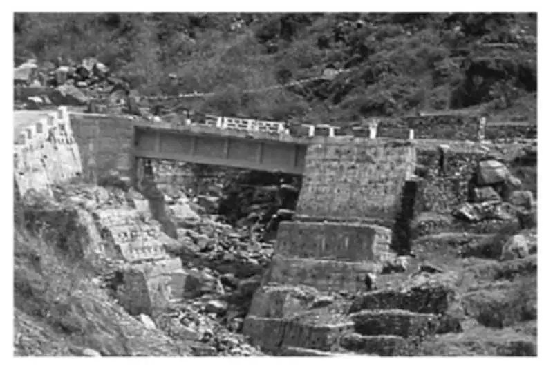 A single-span steel beam bridge constructed over a high-altitude stream