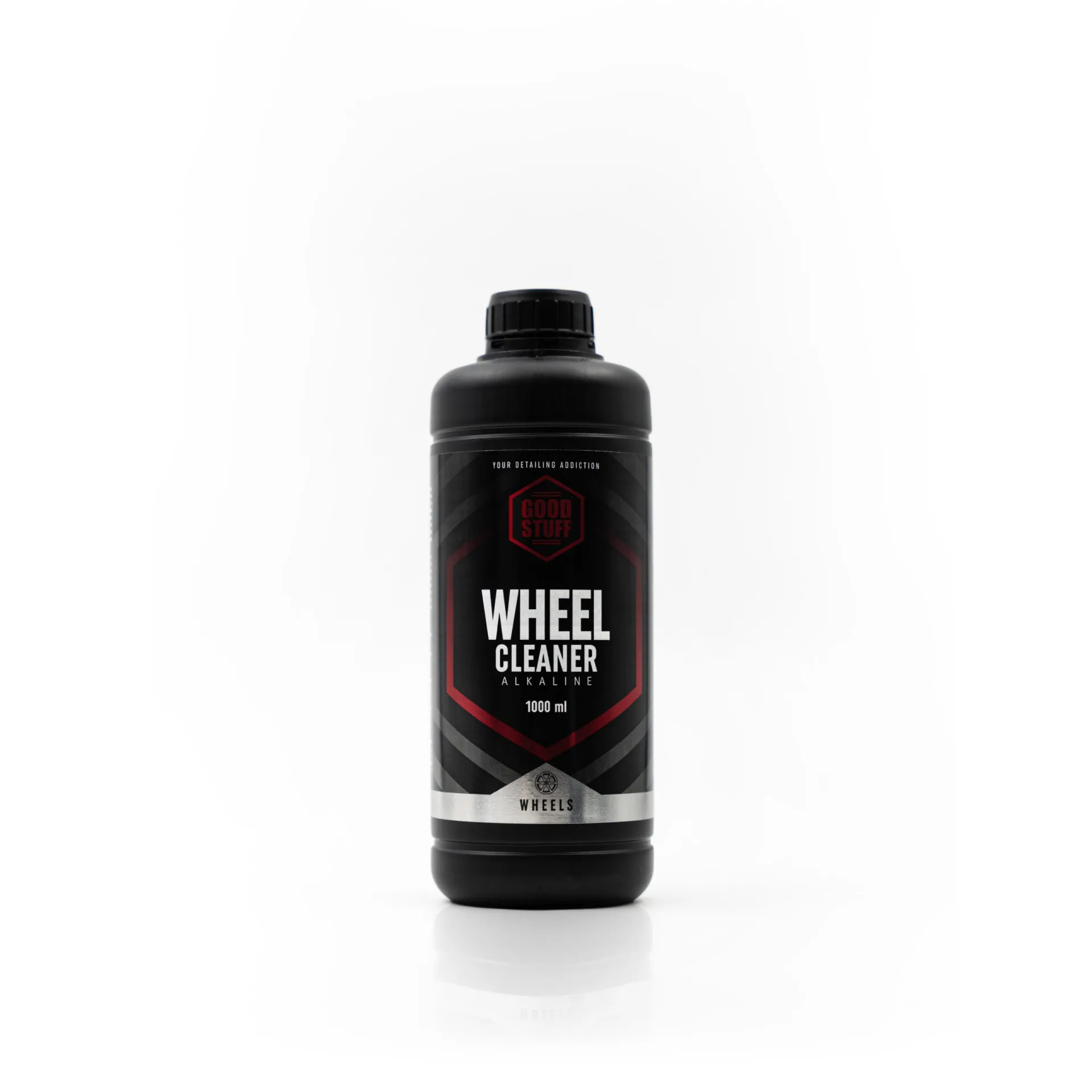 Una botella de plástico negro con la etiqueta Good Stuff Wheel Cleaner Alkaline 1000 ml se encuentra en posición vertical sobre un fondo blanco. La etiqueta presenta colores rojo, negro y blanco con elementos de diseño geométrico.