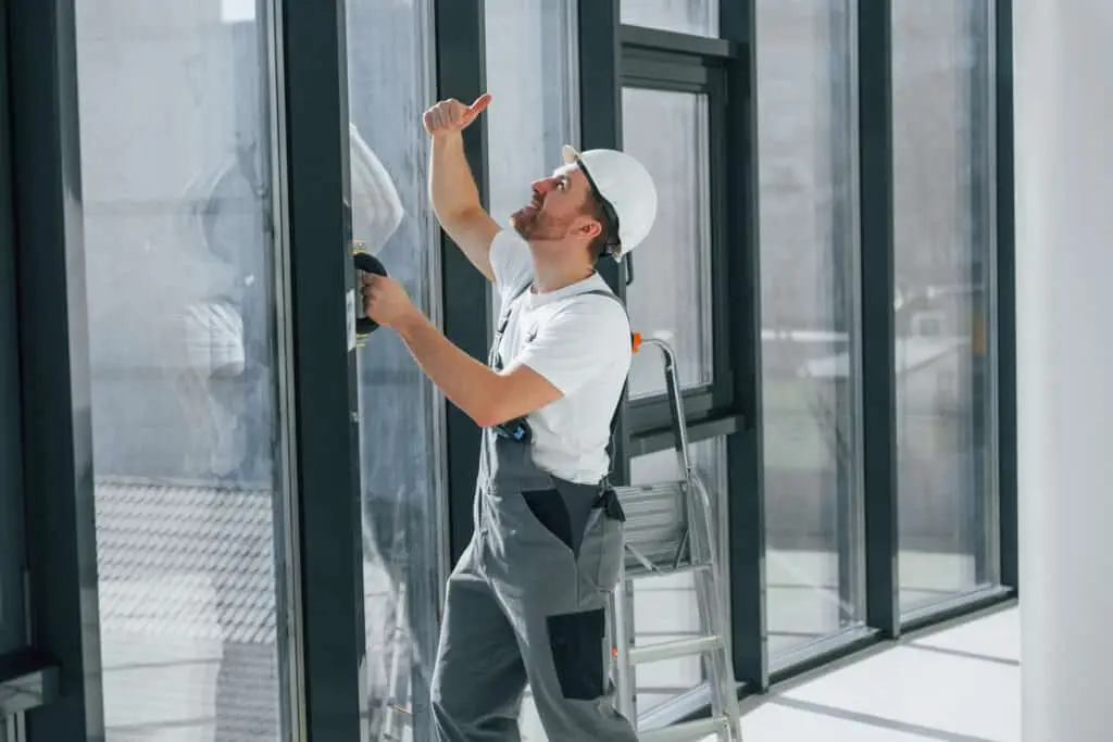 Fensterreinigung. Der Handwerker arbeitet drinnen im modernen Zimmer.