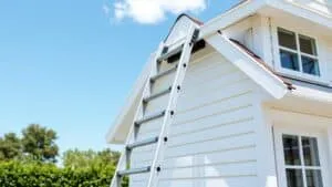 Driedelige ladder tegen de gevel van een Nederlands huis, klaar om de dakgoot schoon te maken.