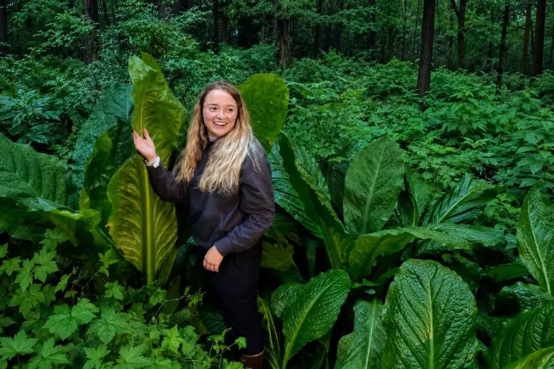 The Quiet Side of Juneau: Why E-Bike Tours Beat the Van 1 Smiling woman on a Juneau rainforest adventure surrounded by lush green foliage.