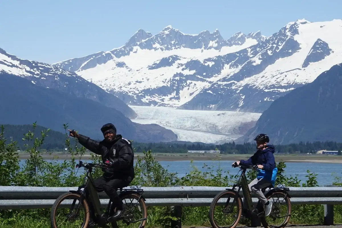 Hidden Gems in Juneau: The Best Places to Visit for Every Kind of Traveler 4 Two people on an eBike tour viewing Mendenhall Glacier and snowy mountains in Juneau, Alaska.