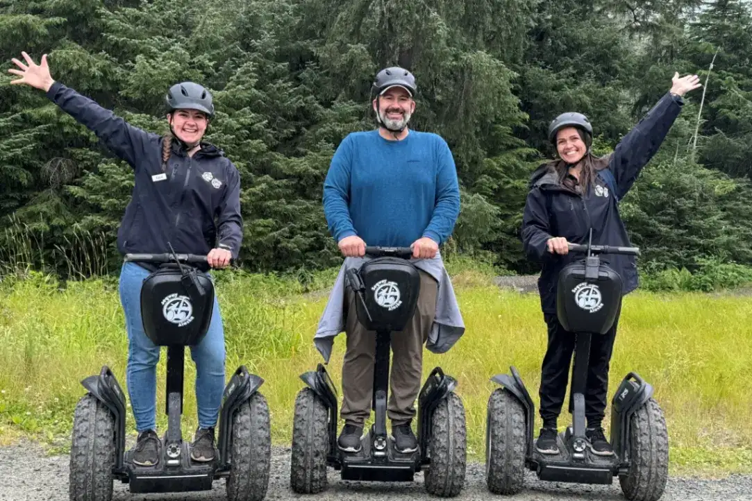 Juneau-alpine-segway-family-fun-smile-tour-1200×800 Three smiling people on iRide Alaska Segways during a Juneau rainforest tour.