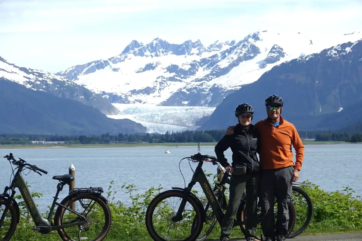 Eco-Friendly Tours in Juneau Alaska: Travel Green with iRide 5 A couple on a Juneau eBike tour overlooking Mendenhall Glacier and mountains.