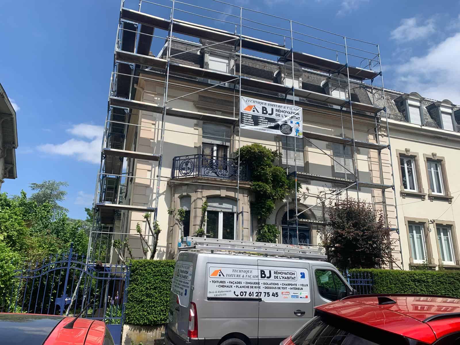 Un fourgon JEB Toiture est garé devant une maison avec échafaudages.
