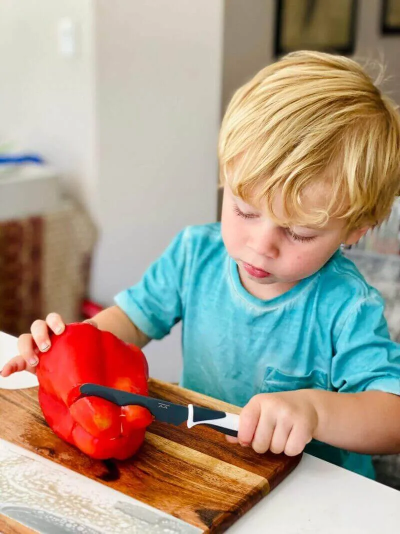 Child cutting red capsicum with a Charcoal KiddiKutter